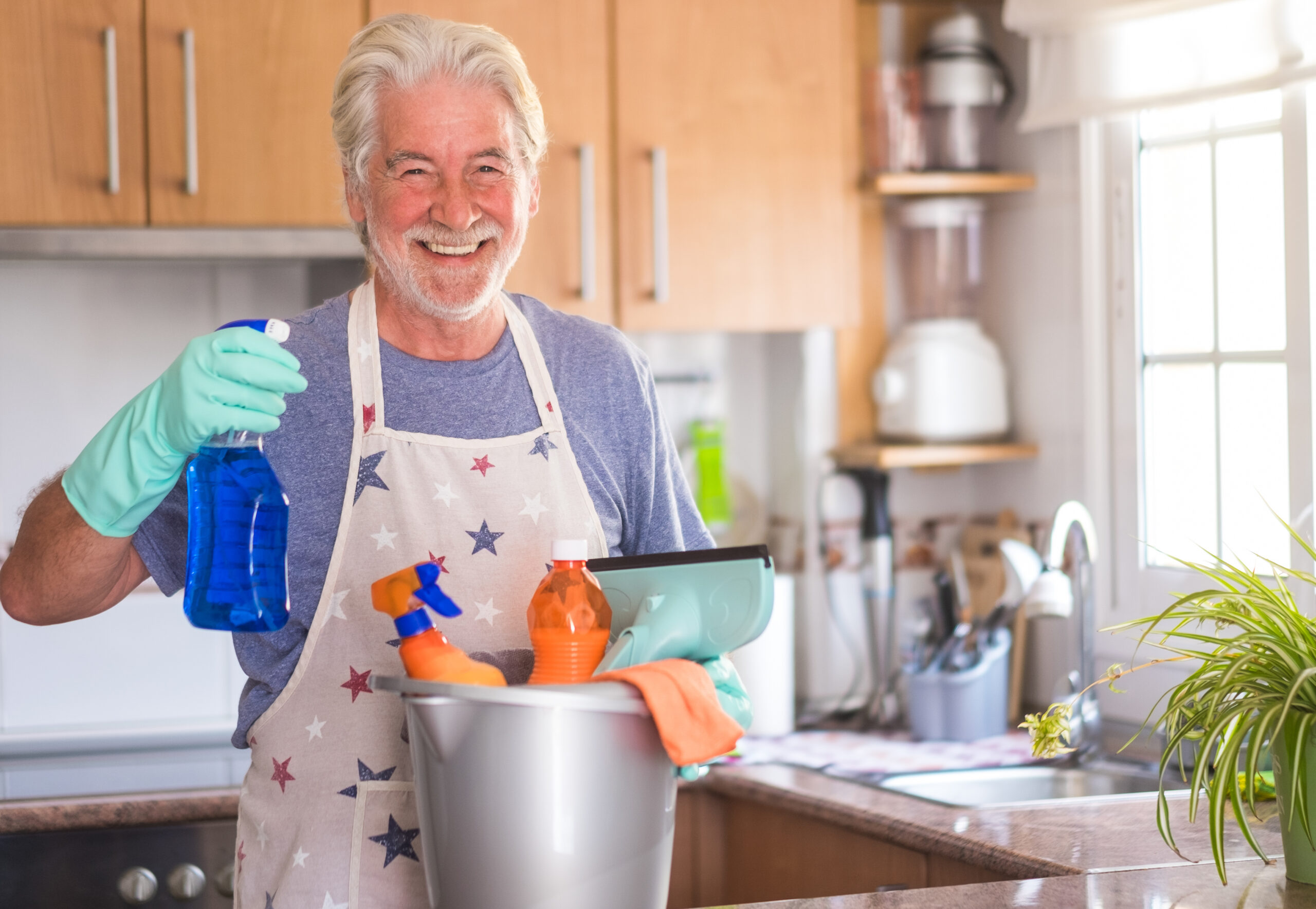 A senior smiling man ready to start housework. He holds a plasti